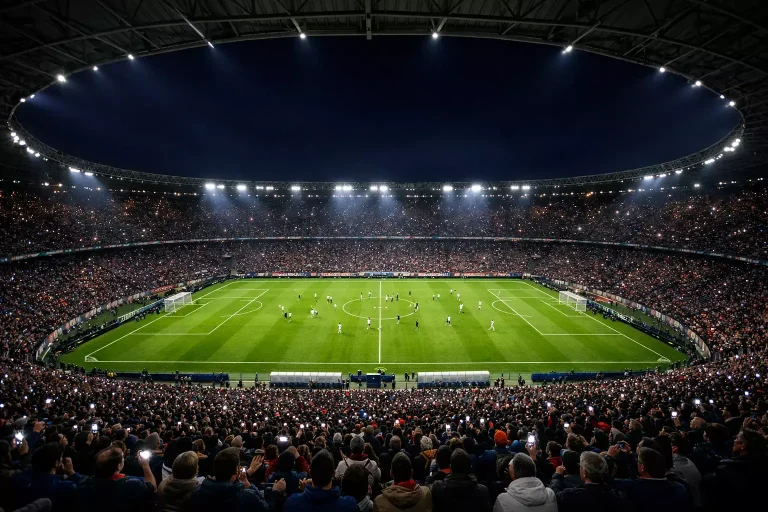 Stadio di calcio pieno di tifosi durante una partita in notturna